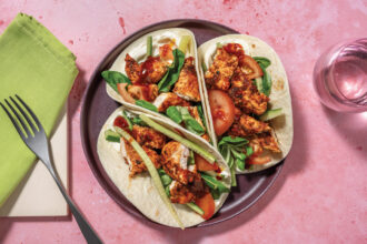 Three tacos willed with sticky chicken and green salad.